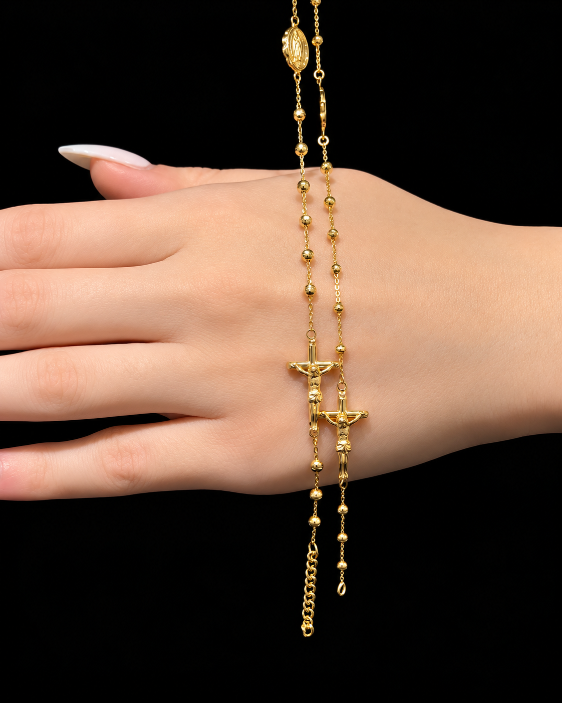Two gold rosaries with crucifixes displayed over a hand