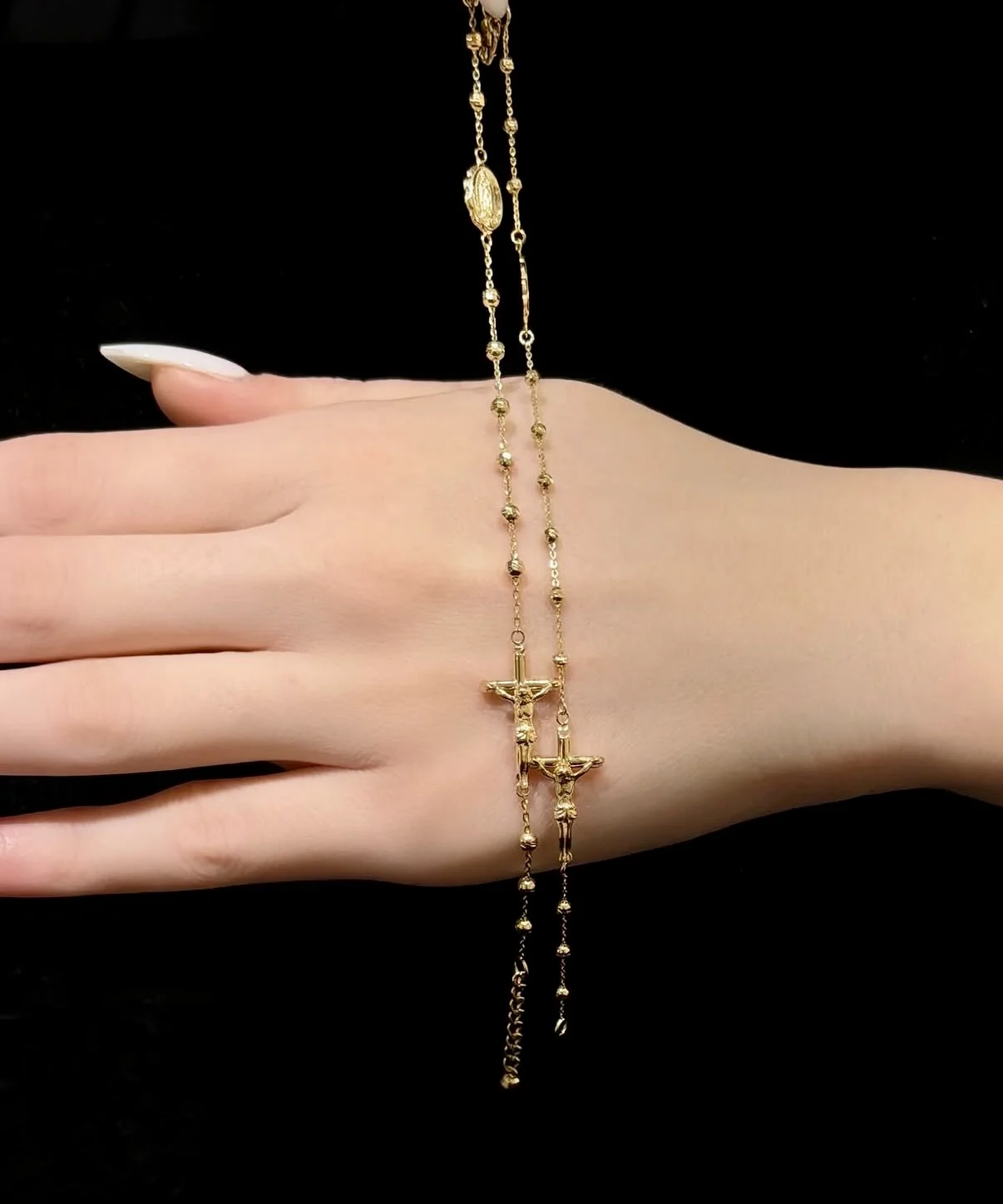 Gold rosary with crucifix and medallion held in hand