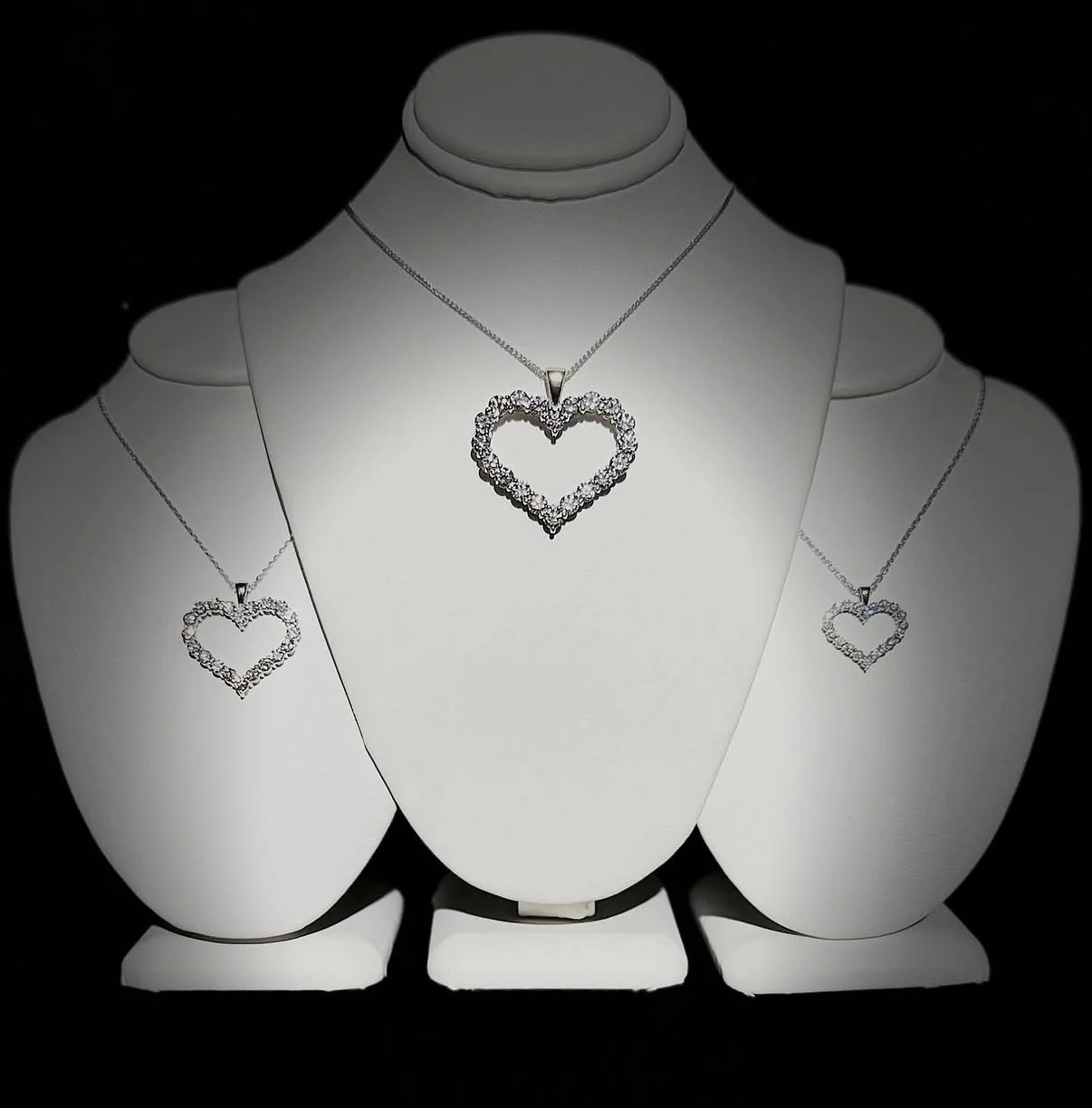 Three diamond heart pendant necklaces displayed on white busts