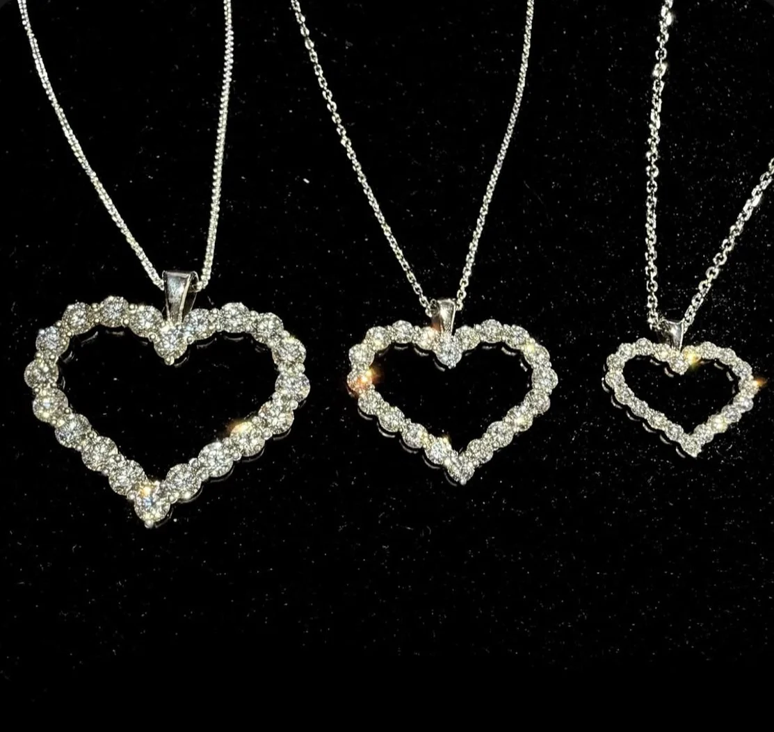 Three diamond heart pendant necklaces arranged on black velvet