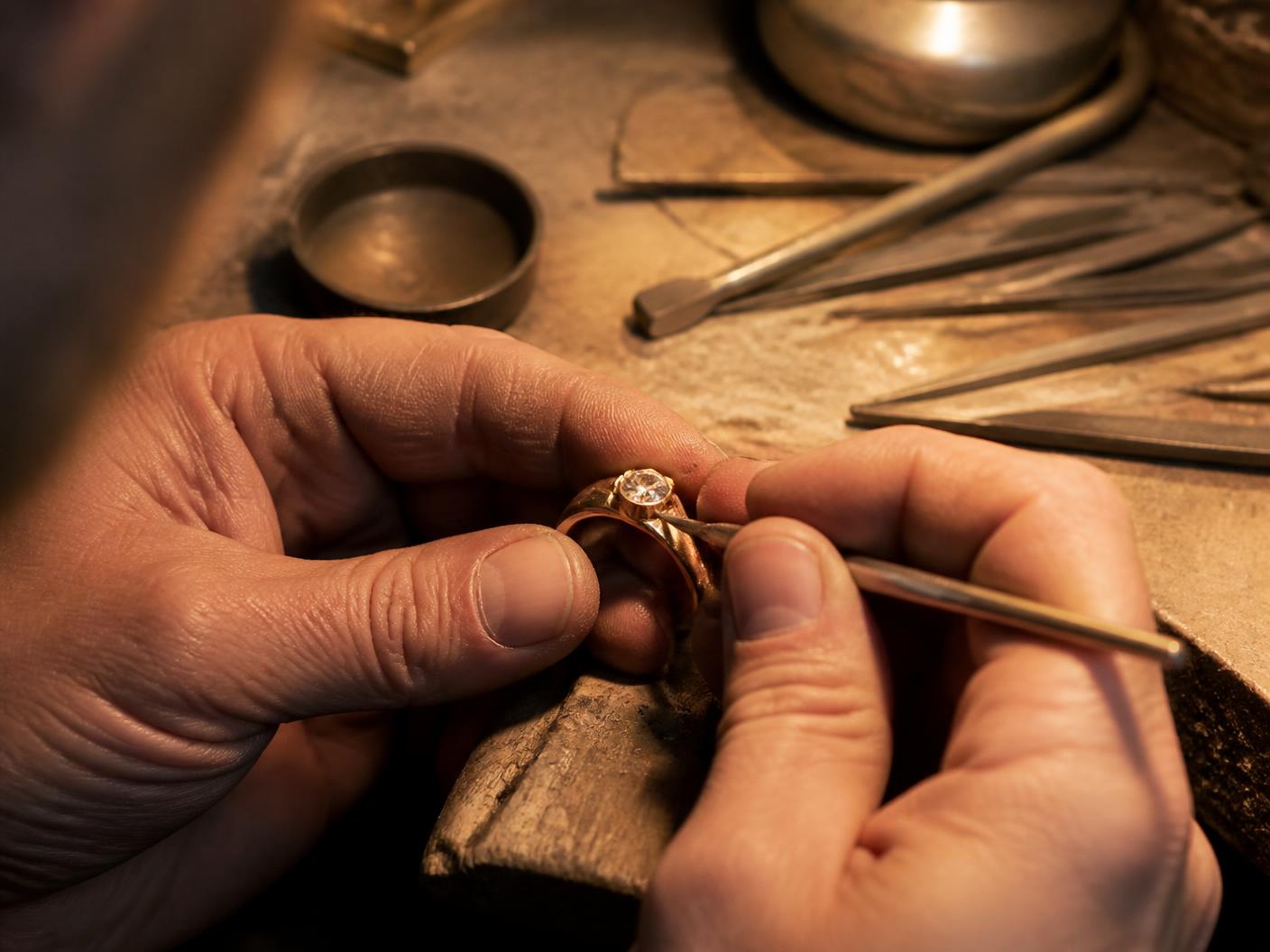 Jeweler's hands working on a gold ring at the bench