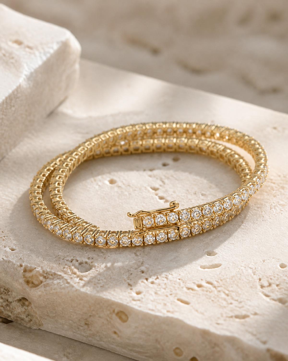 Gold diamond line bracelet coiled on pale stone