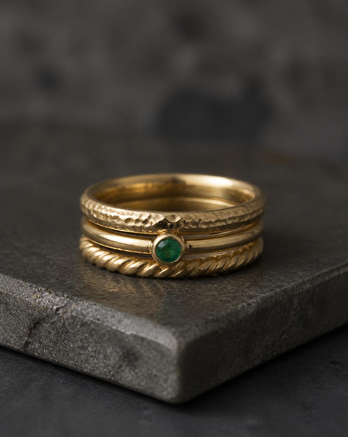 Stack of three gold rings, one set with a green gemstone